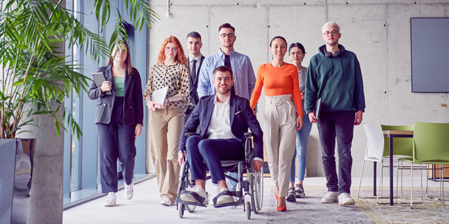 Different people standing next to each other with a person in a wheelchair in front